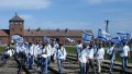 A visitor to Auschwitz carries the Israeli flag as a group examines a boxcar used to transport Jews to extermination and concentration camps.