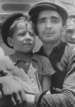 Eight-year-old Yisrael Meir (Lulek) Lau is held by a fellow Buchenwald survivor, Elazar Schiff, as they arrive in Palestine Israel aboard the RMS 