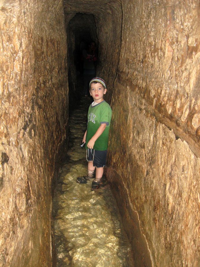 A Jewish lad explores Hezekiah's tunnel with a flashlight in hand.