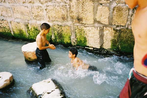 Israeli children, who have exited Hezekiah's Tunnel at the Pool of Siloam, play in the water that originates at the Gihon Spring.