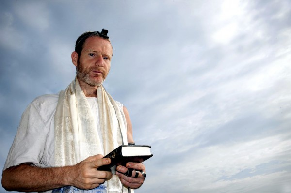 A Jewish man prepares to recite morning prayer.