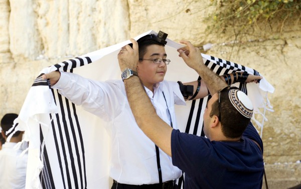 A Jewish father helps his son adjust his tallit gadol during the boy's bar mitzvah at the Western (Wailing) Wall.