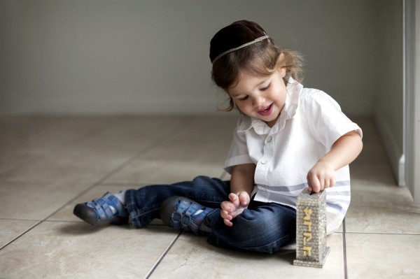 A Jewish boy puts money in the pushke, a box kept in Jewish homes for collecting funds to give to the poor and other benevolence.