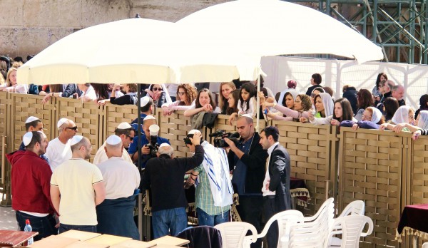 Women observe the Bar Mitzvah of a male relative from behind the fence during a Bar Mitzvah in the men's section at the Western (Wailing) Wall. (Photo by Dan Lundberg)