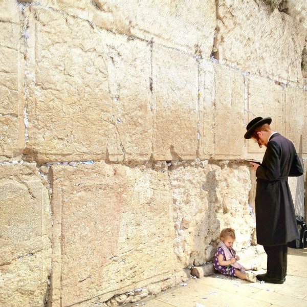 A child sits at her father's feet as he prays at the Western (Wailing) Wall in Jerusalem. (Israel Tourism photo by VuTheara Kham)