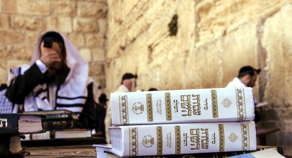 Jewish men pray Shacharit (morning prayers) at Jerusalem's Western (Wailing) Wall. In the foreground are siddurs (Jewish prayer books).