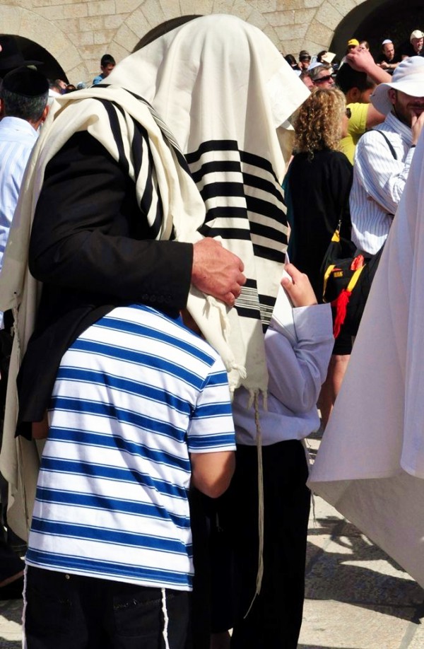 A father pulls his sons under his tallit (prayer shawl) during the Priestly Blessing at the Western Wall in Jerusalem. (Photo by Lilach Daniel)