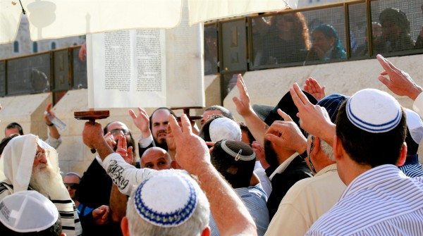 Men reach out to pay respect to the Torah as it is raised at the Western (Wailing) Wall in Jerusalem. (Photo by opalpeterliu)