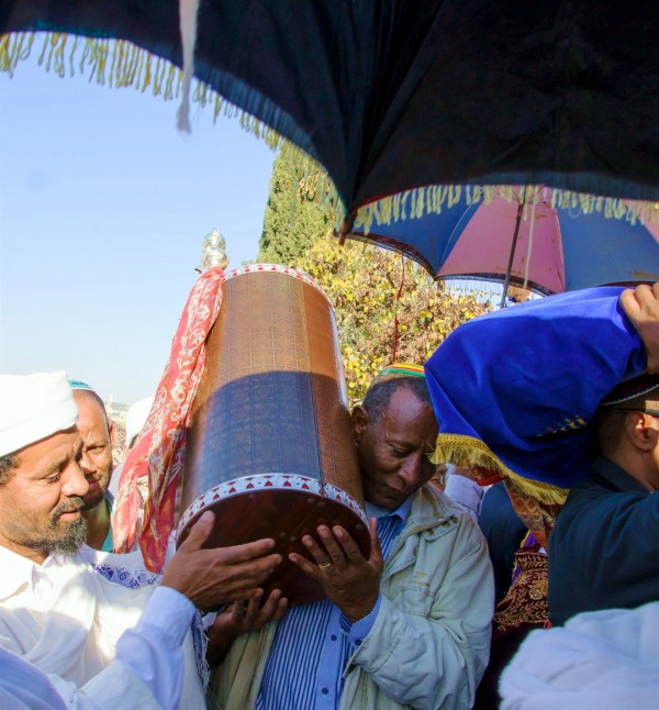 An Ethiopian Jewish man and a Kes, a religious leader of the Ethiopian Jews, carry the Torah.