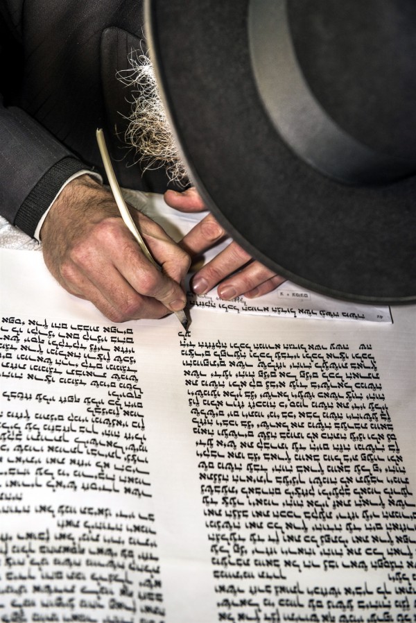 An Orthodox Jewish man writes a Torah scroll.