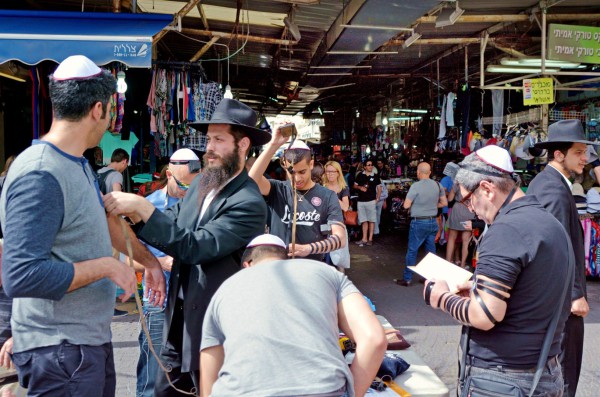 Ultra-Orthodox Jewish men in Tel Aviv show passersby how to put on tefillin (phylacteries) and pray.