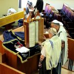 Reading from a Torah scroll encased in a protective Torah tik (case).