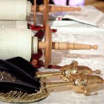 Open Torah scroll with an embroidered Torah mantle (cover) and silver finials for adorning the staves.