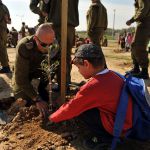 An Israel Defense Forces solder helps a child plant a tree for Tu B'Shvat.