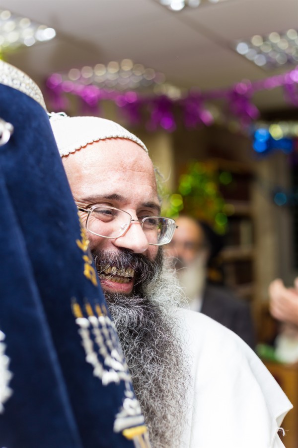 An Orthodox Jewish man embraces a Torah scroll.