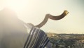 Jewish man blowing shofar over Jerusalem