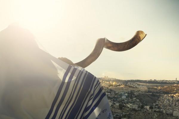 Jewish man blowing shofar over Jerusalem