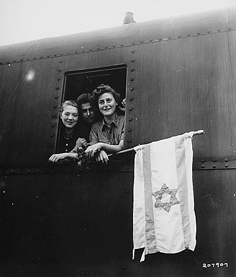 Released inmates of Buchenwald concentration camp in Germany, holding a homemade flag on their way to Israel, 1945. This design had already become the official flag of the World Zionist Organization and in 1948, the reborn state of Israel.