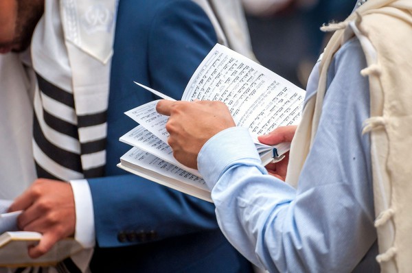 Men wearing tallit (prayer shawls) read from their siddurs (prayer books).  